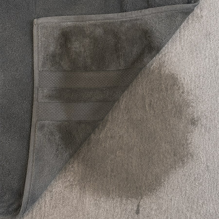 A bath towel folded back, showing liquid that has soaked straight through
